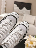 White Chanel low-top sneakers close-up with patterned laces and black logo trim