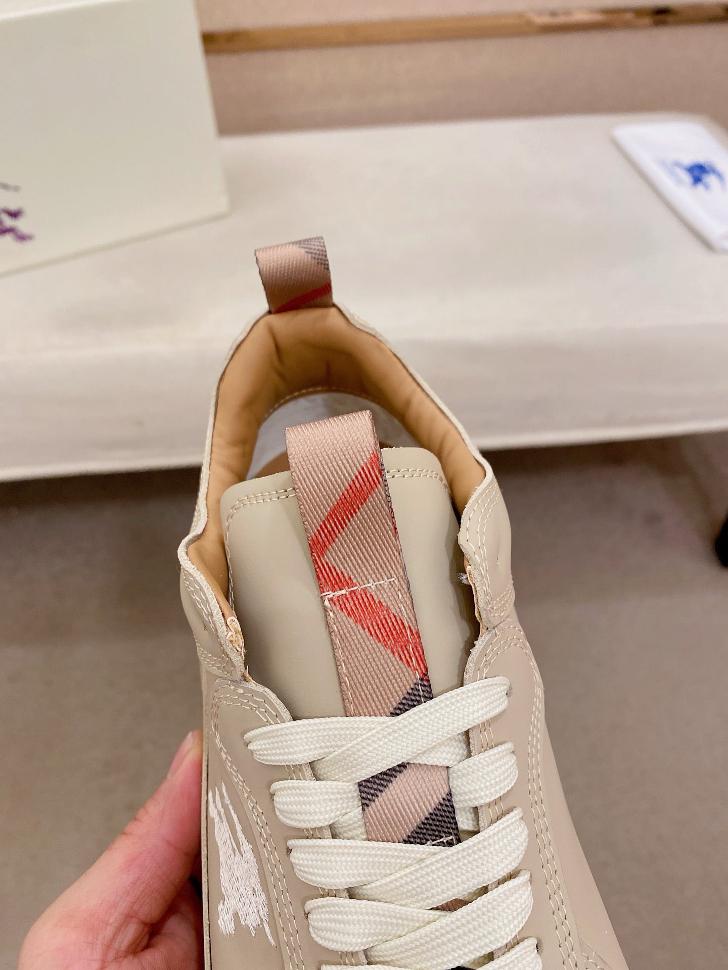 Cream sneaker interior showing plaid lining and beige lace-up tongue label