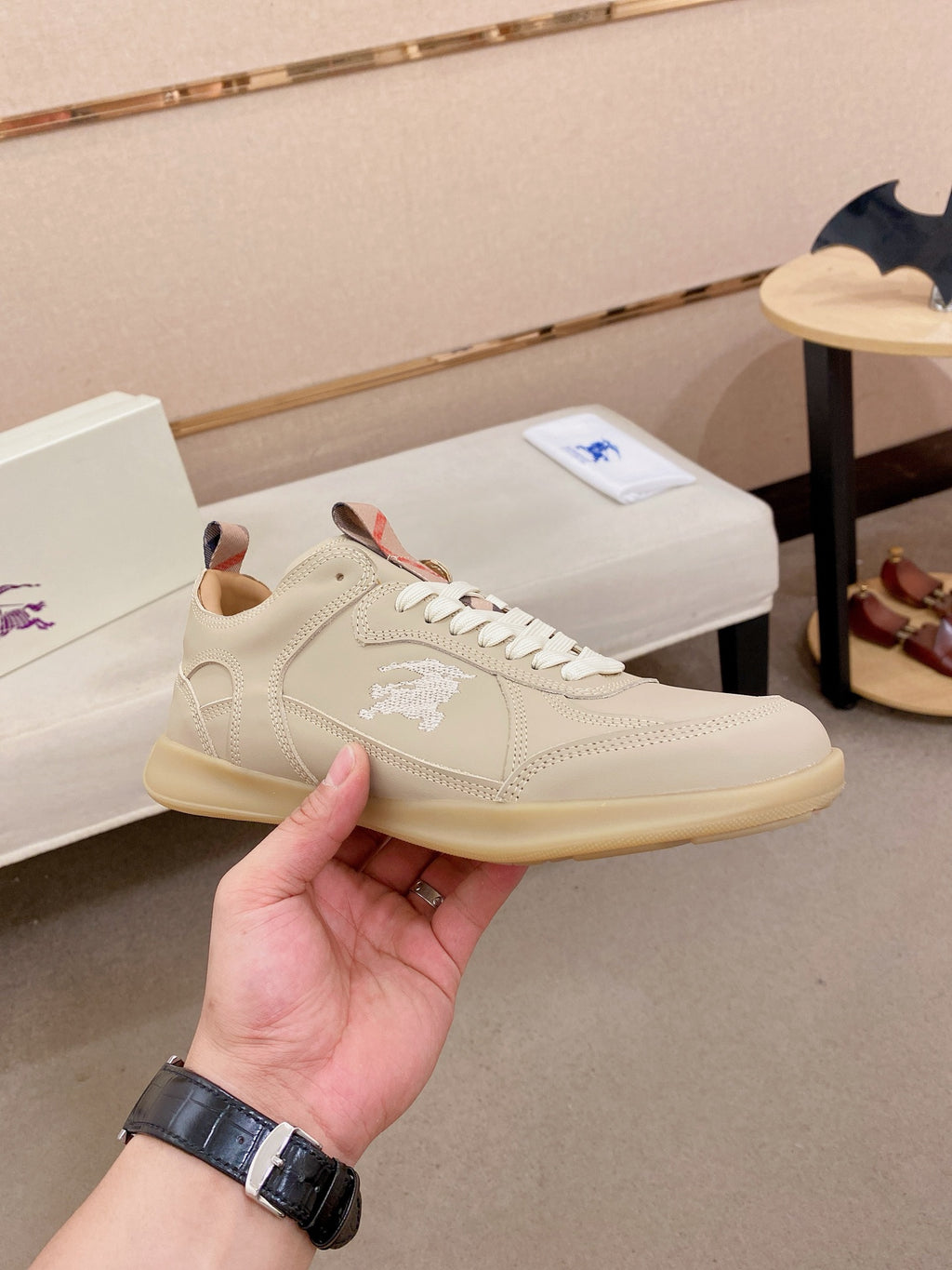 Cream low-top sneaker with lace-up closure, stitched logo and tan rubber sole