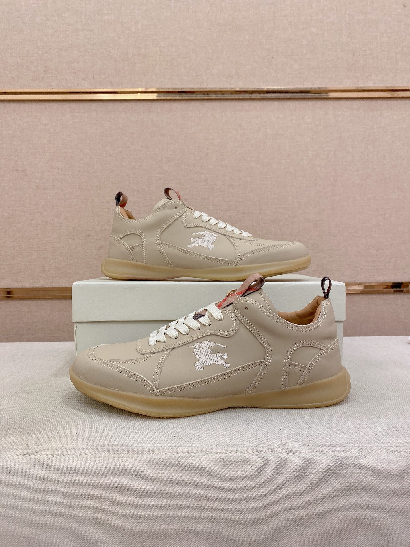 Pair of cream lace-up sneakers on box with embroidered logo on side