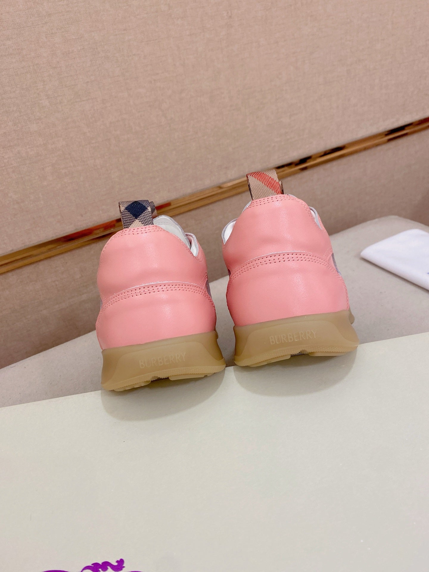 Pink sneaker pair back view with beige heel and lace-up tabs