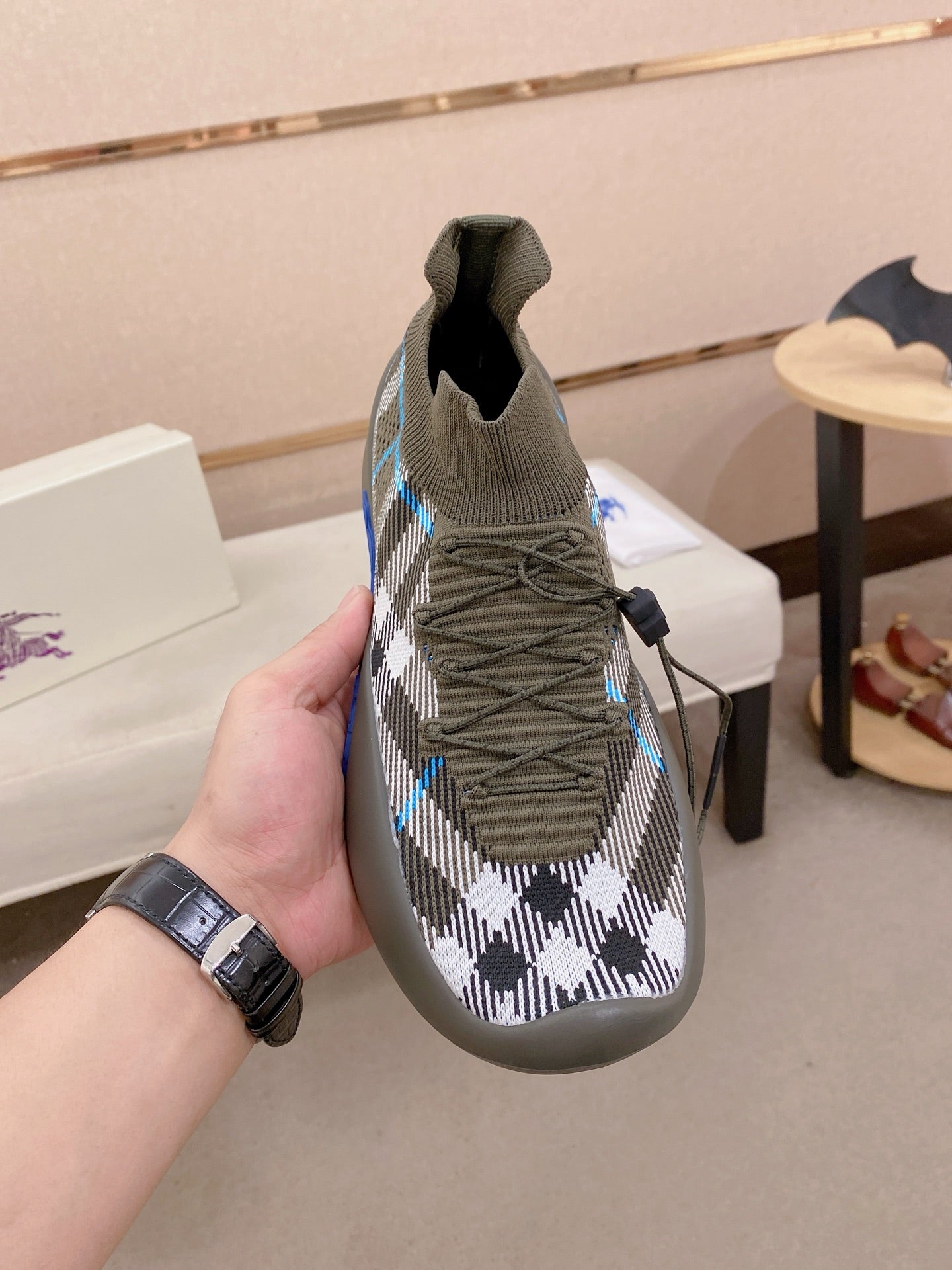 Gray knit sneaker with black-and-white plaid upper, lace-up, and blue accent sole