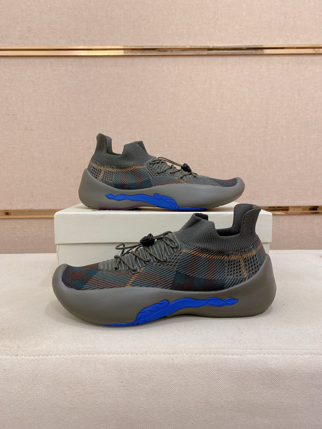 Pair of gray knit sneakers with multicolor pattern and blue sculpted soles