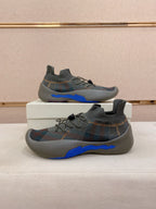 Pair of gray knit sneakers with multicolor pattern and blue sculpted soles