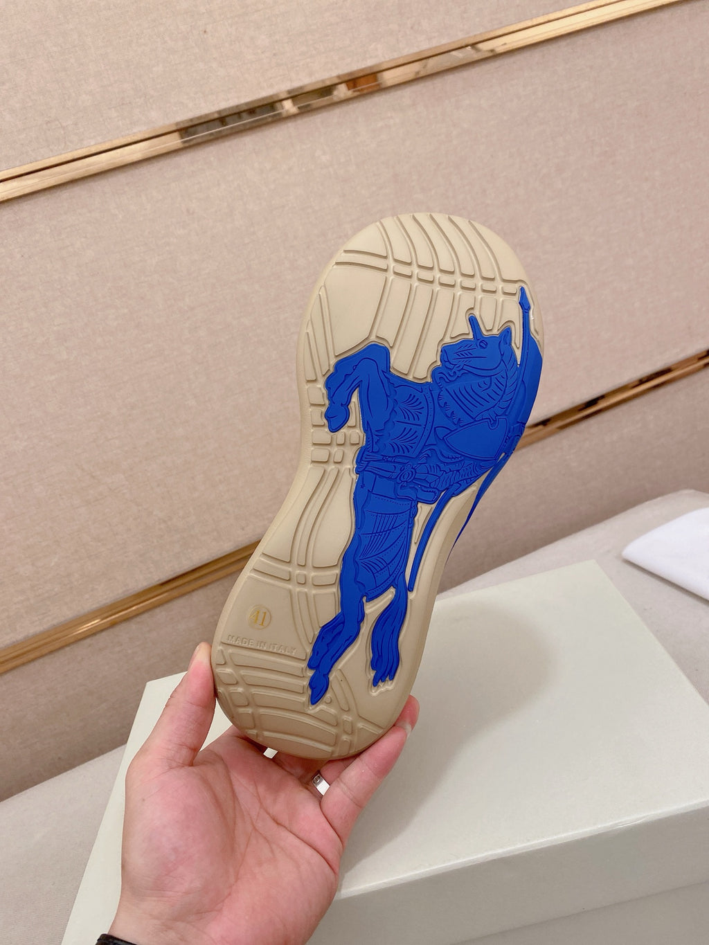 Rubber outsole of knit sneaker with blue traction pattern on beige sole