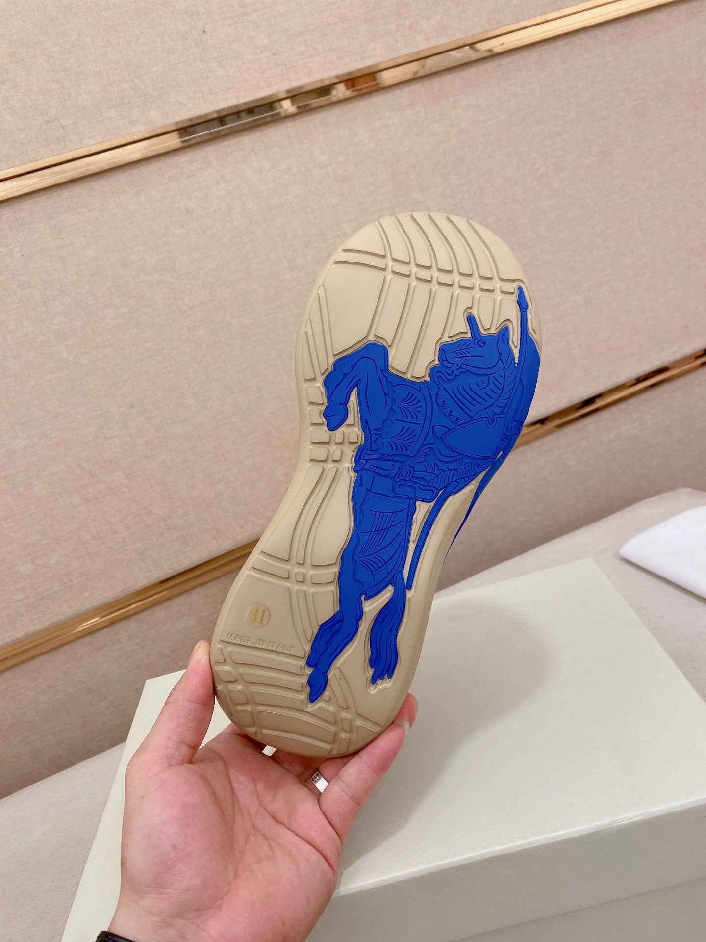 Rubber outsole of knit sneaker with blue traction pattern on beige sole