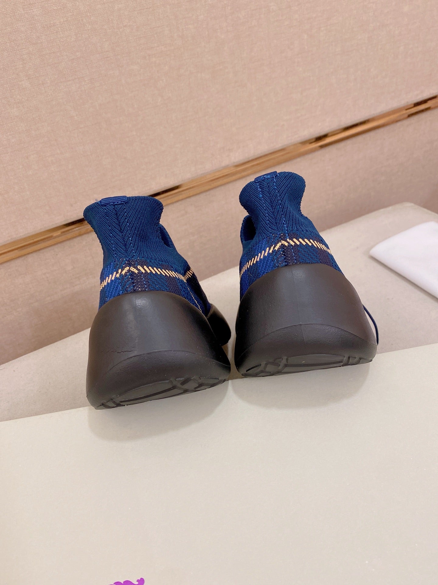 Blue knit sneakers with black heels and soles, rear view