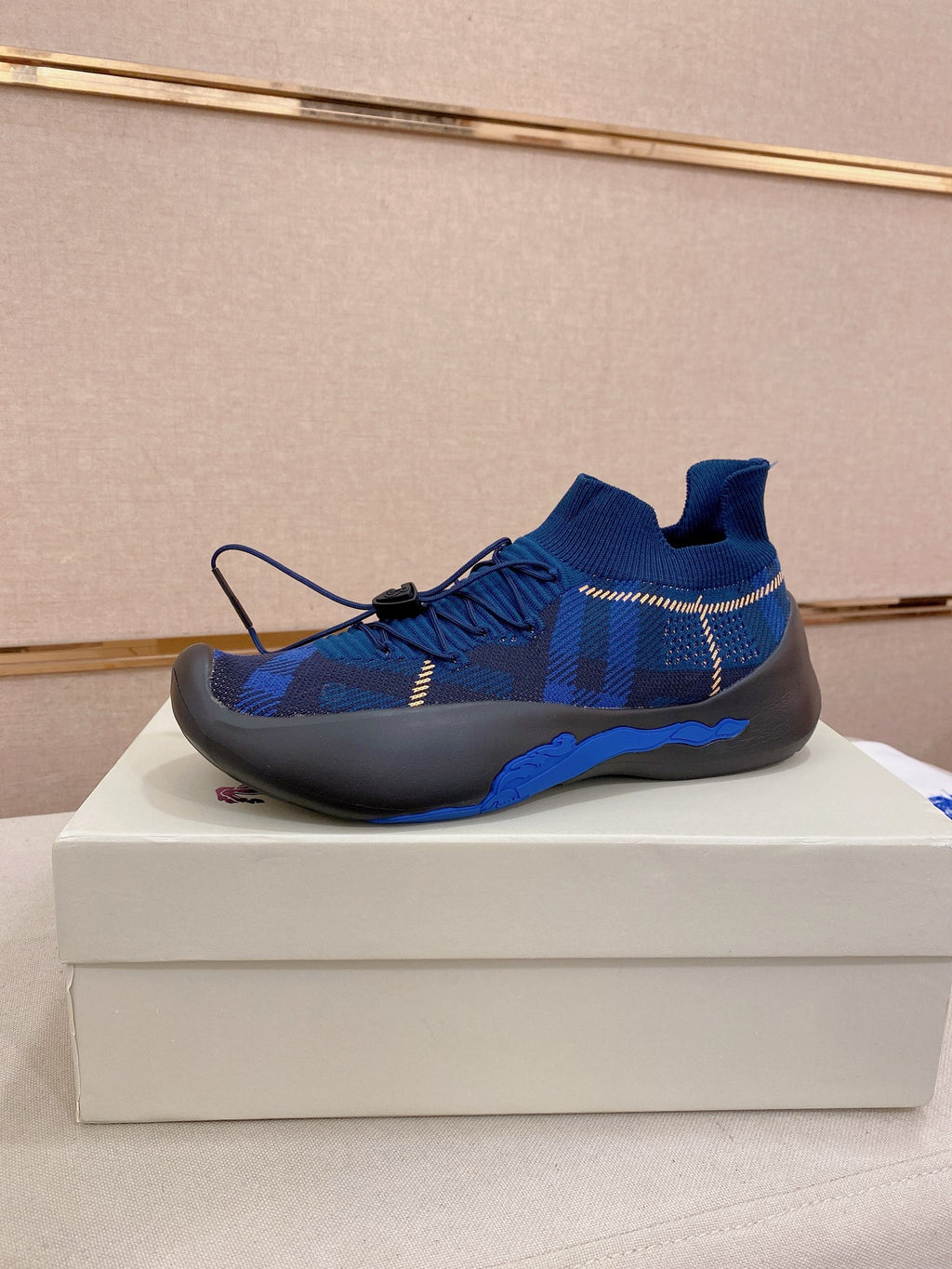 Blue knit sneaker with black rubber sole and blue laces, side view