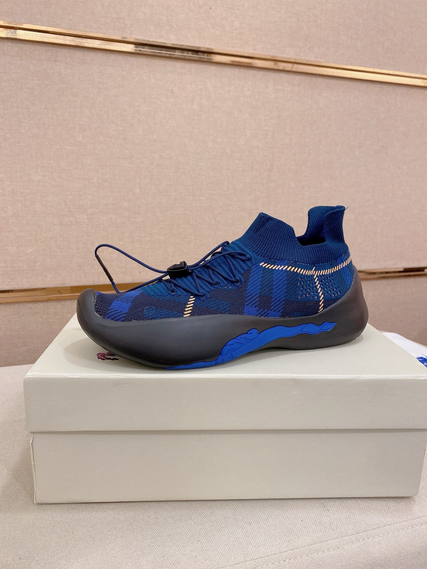Blue knit sneaker with black rubber sole and blue laces, side view