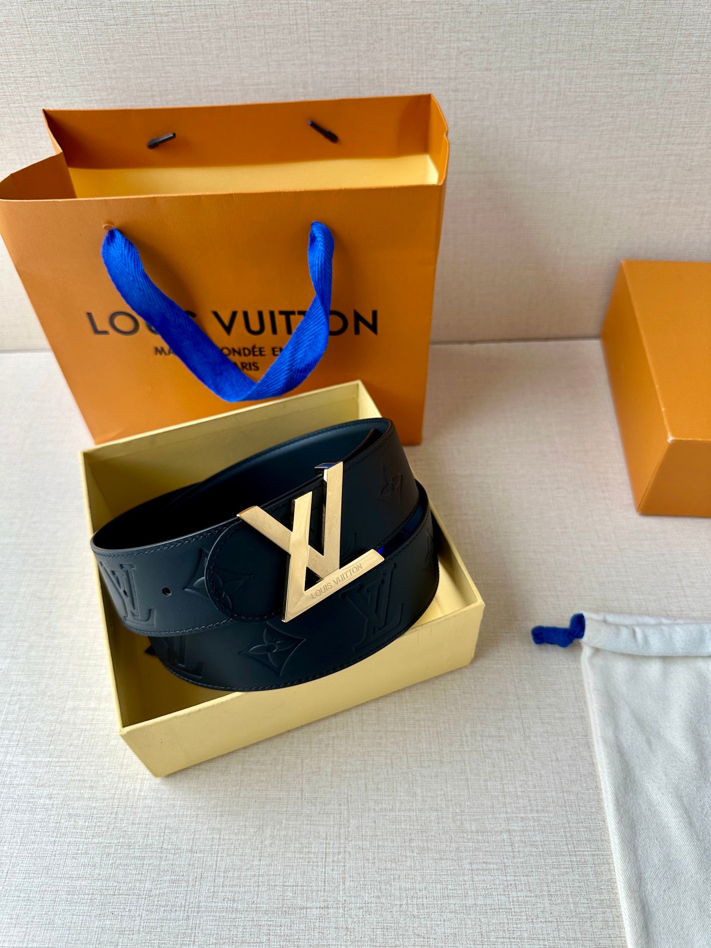 Black Louis Vuitton belt with embossed monogram leather and gold-toned LV buckle.