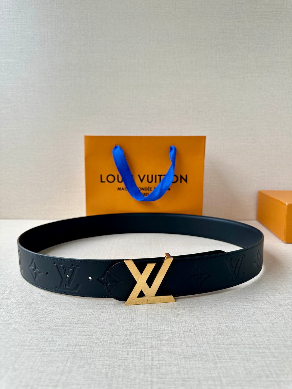 Black Louis Vuitton belt with embossed monogram pattern and gold-toned LV buckle.