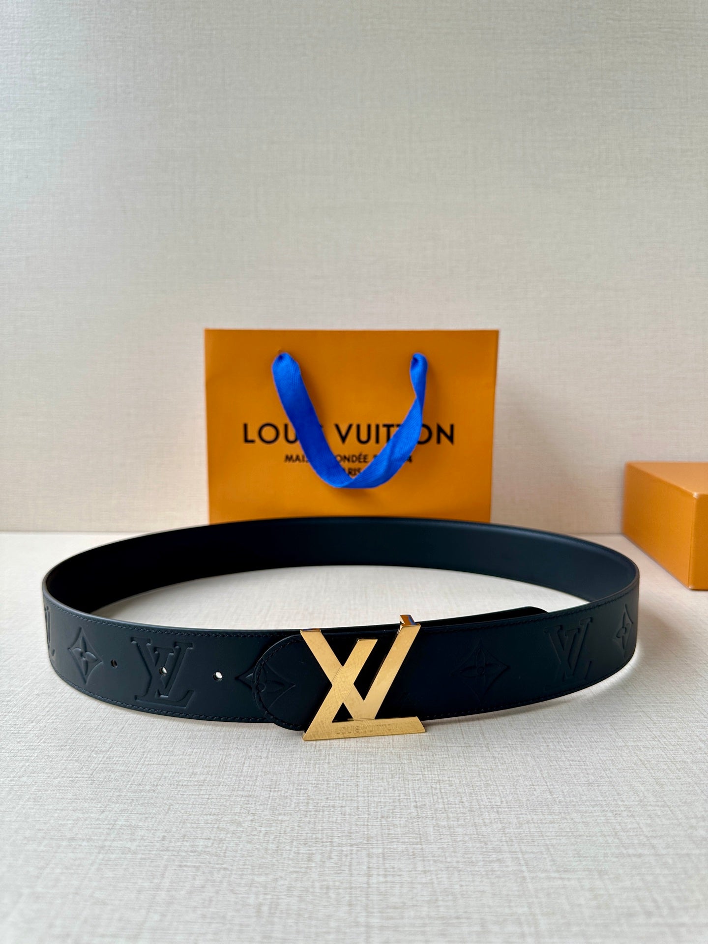 Black Louis Vuitton belt with embossed monogram pattern and gold-toned LV buckle.