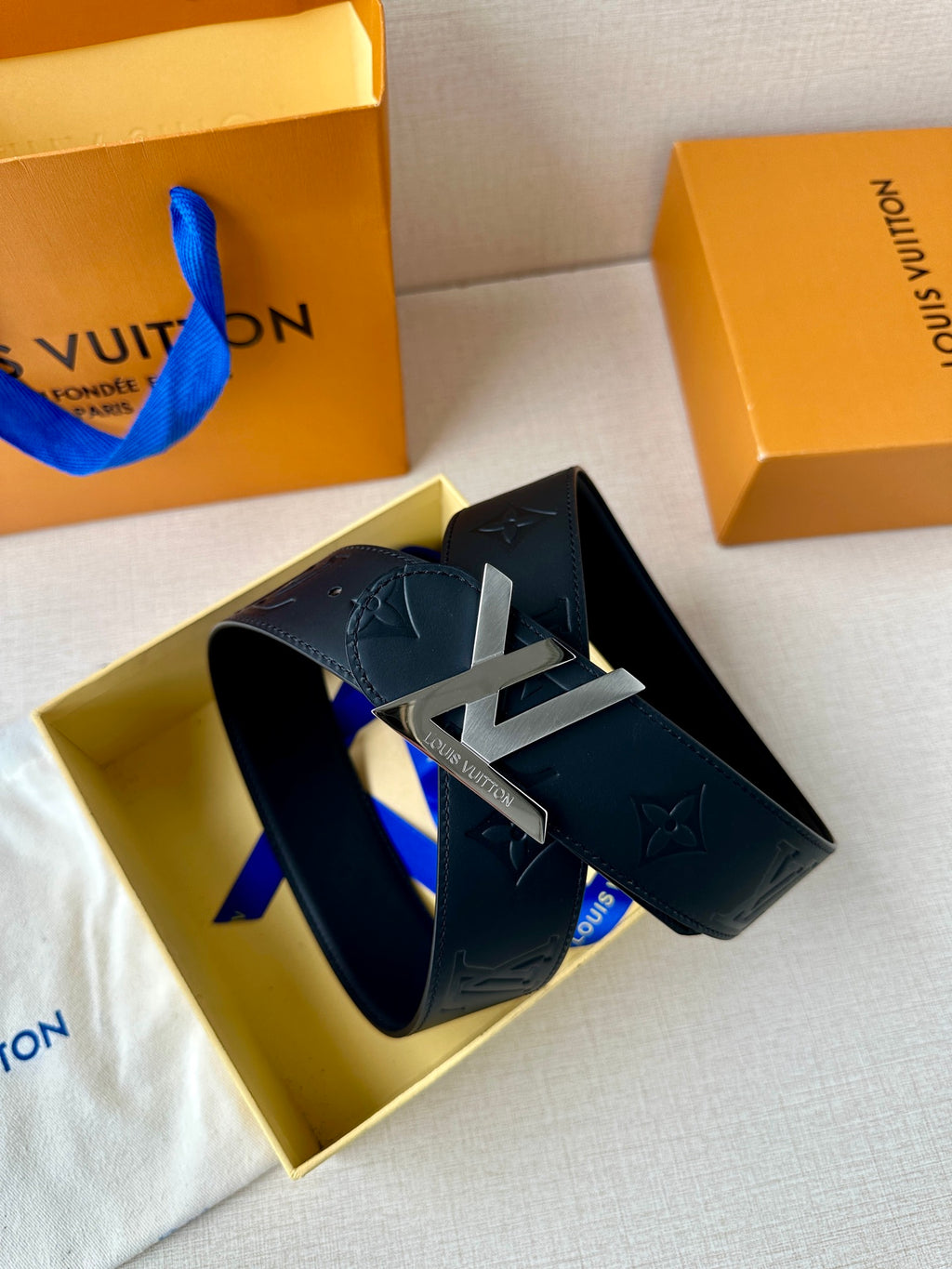 Black Louis Vuitton belt in box with gold-toned LV buckle and embossed monogram leather.