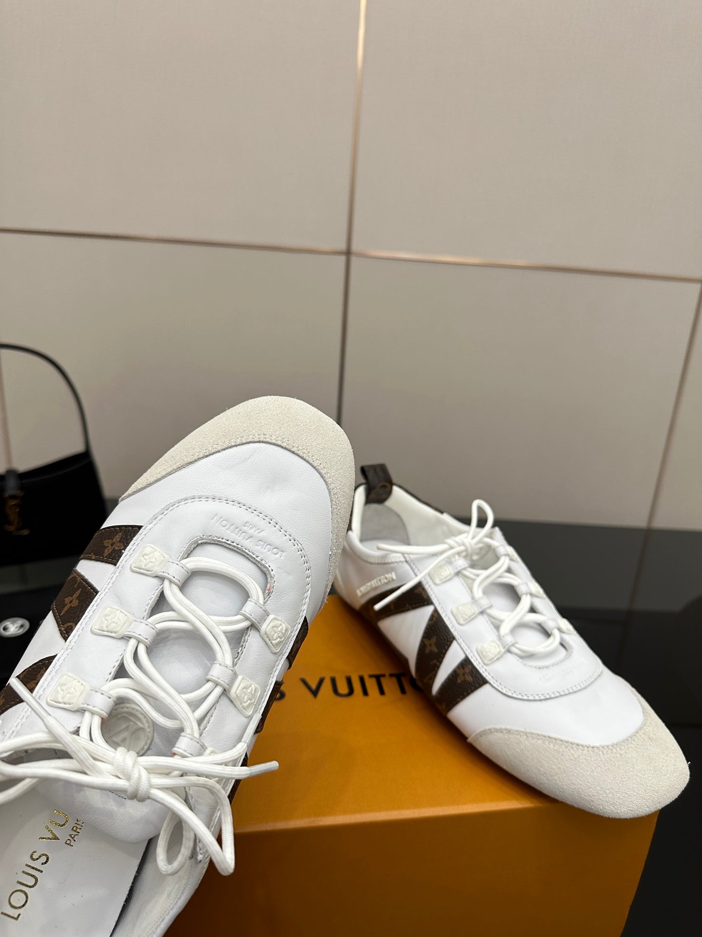 Louis Vuitton white sneakers close-up with white laces and brown monogram side trim