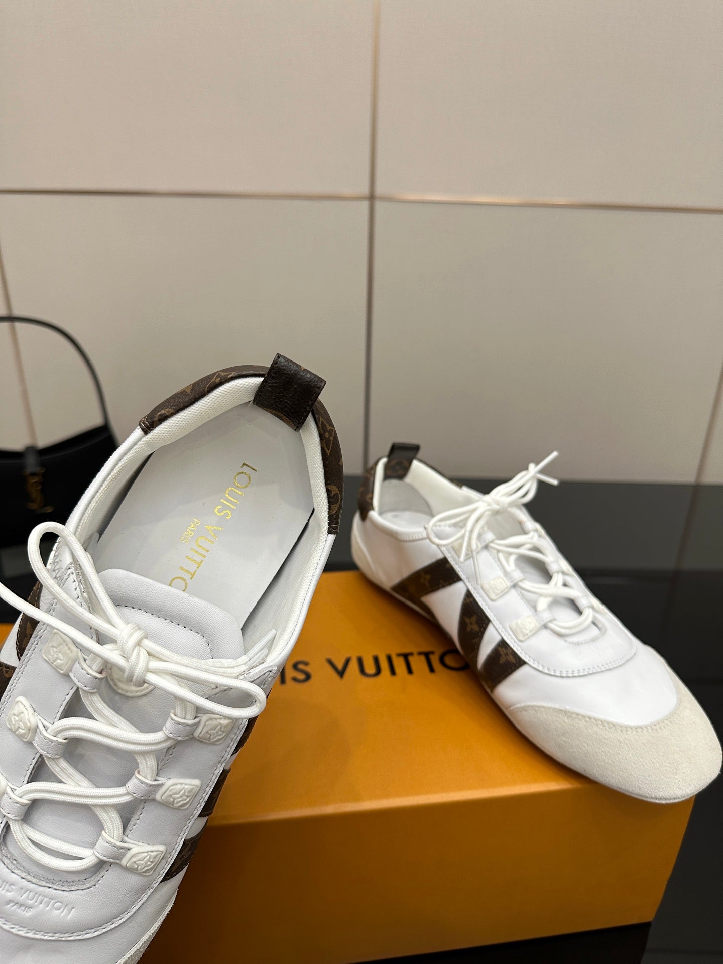 Louis Vuitton white sneakers close-up with printed insole and brown monogram patch