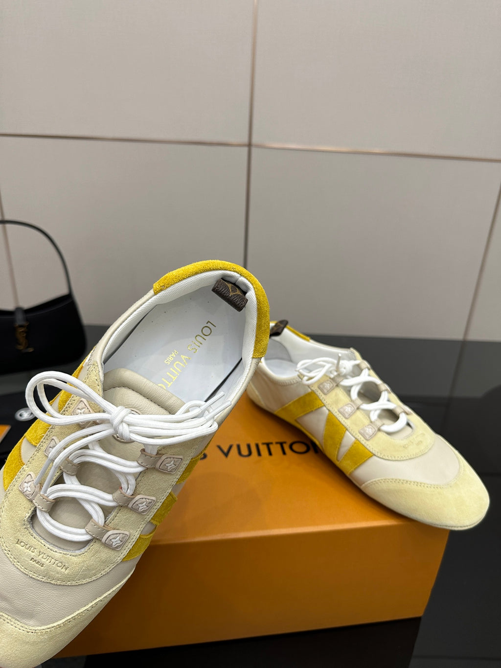 Louis Vuitton sneakers close-up, cream uppers with yellow collar and white laces