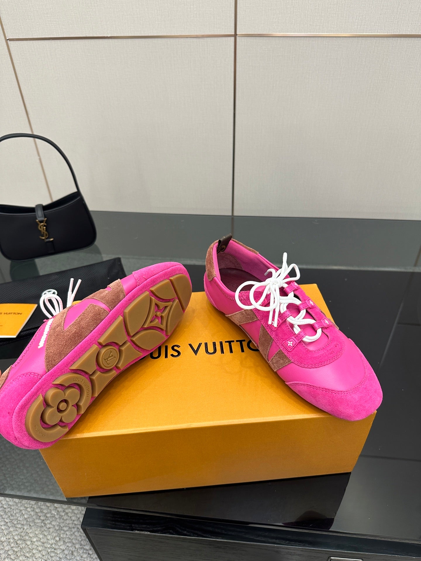Pink sneakers with patterned outsoles featuring a tan logo design