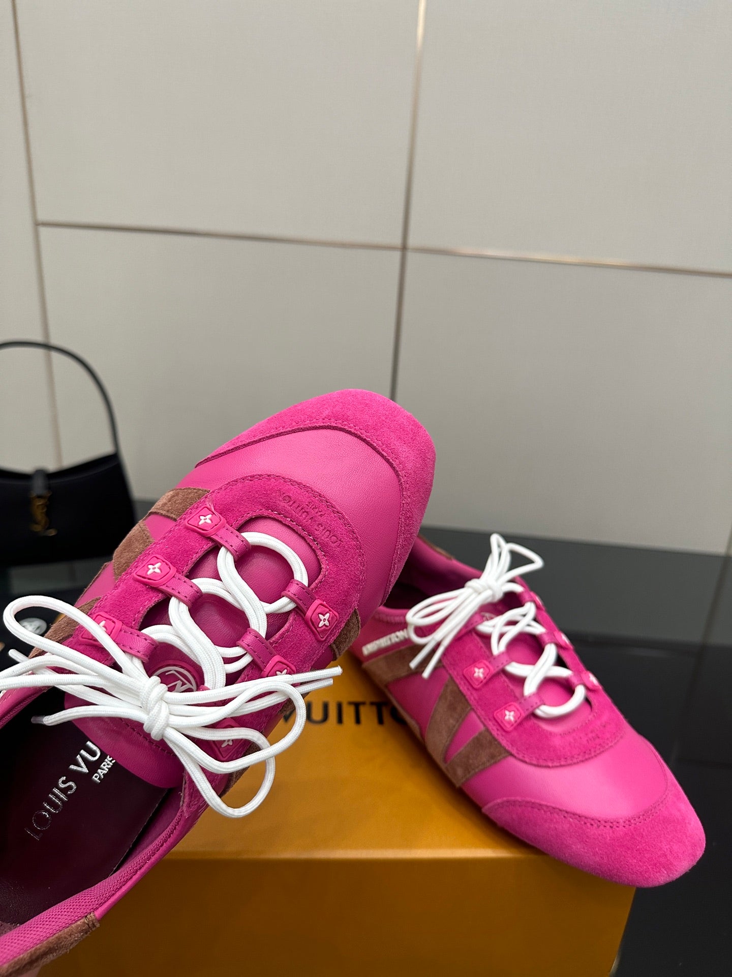 Close-up of pink sneaker with white laces and logo detail near eyelets