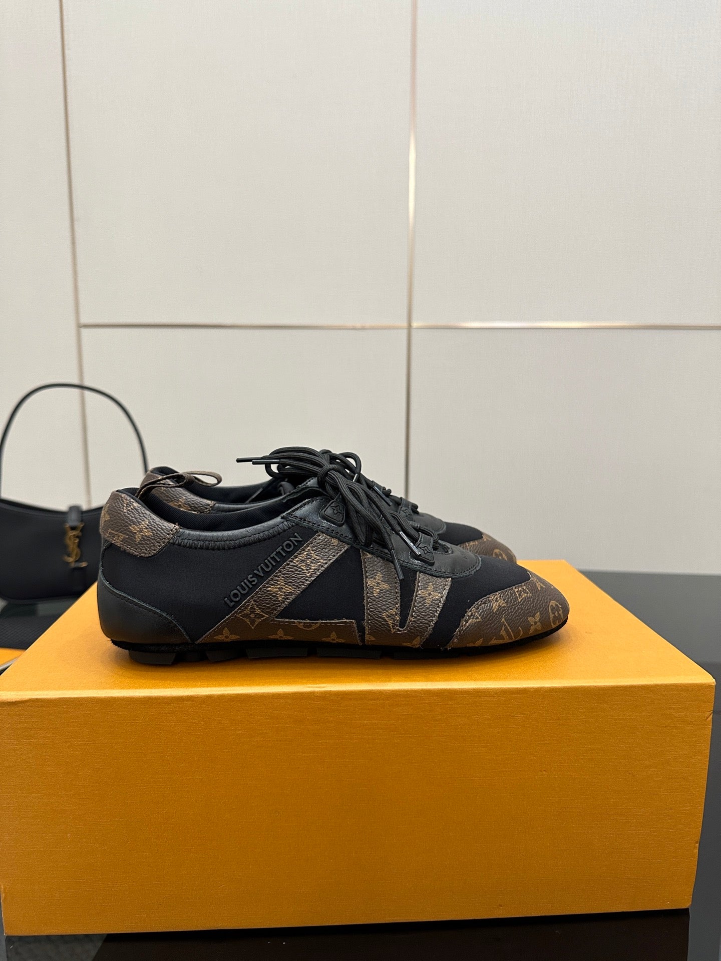 Louis Vuitton lace-up sneakers on side view, dark monogram pattern and black laces