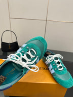 Close-up of teal low-top sneakers with white laces and logo star patch detail