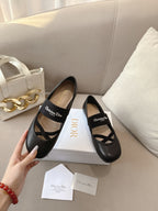 Black women's ballet flats on white boxes with crisscross strap and logo patch.