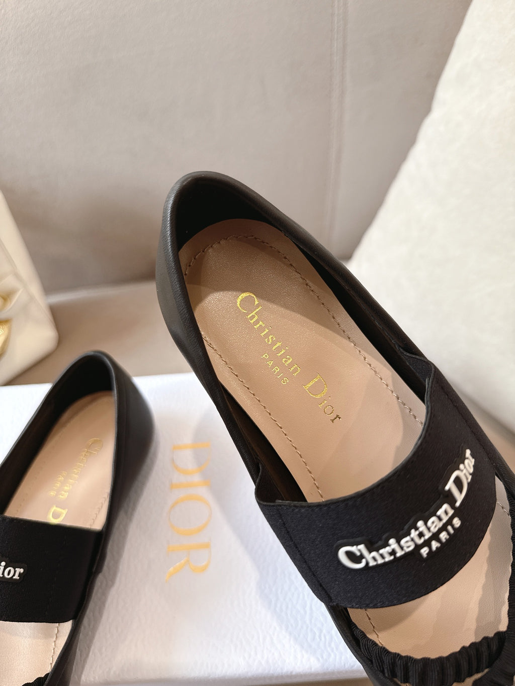 Black women's ballet flats with logo top strap and light tan interior.