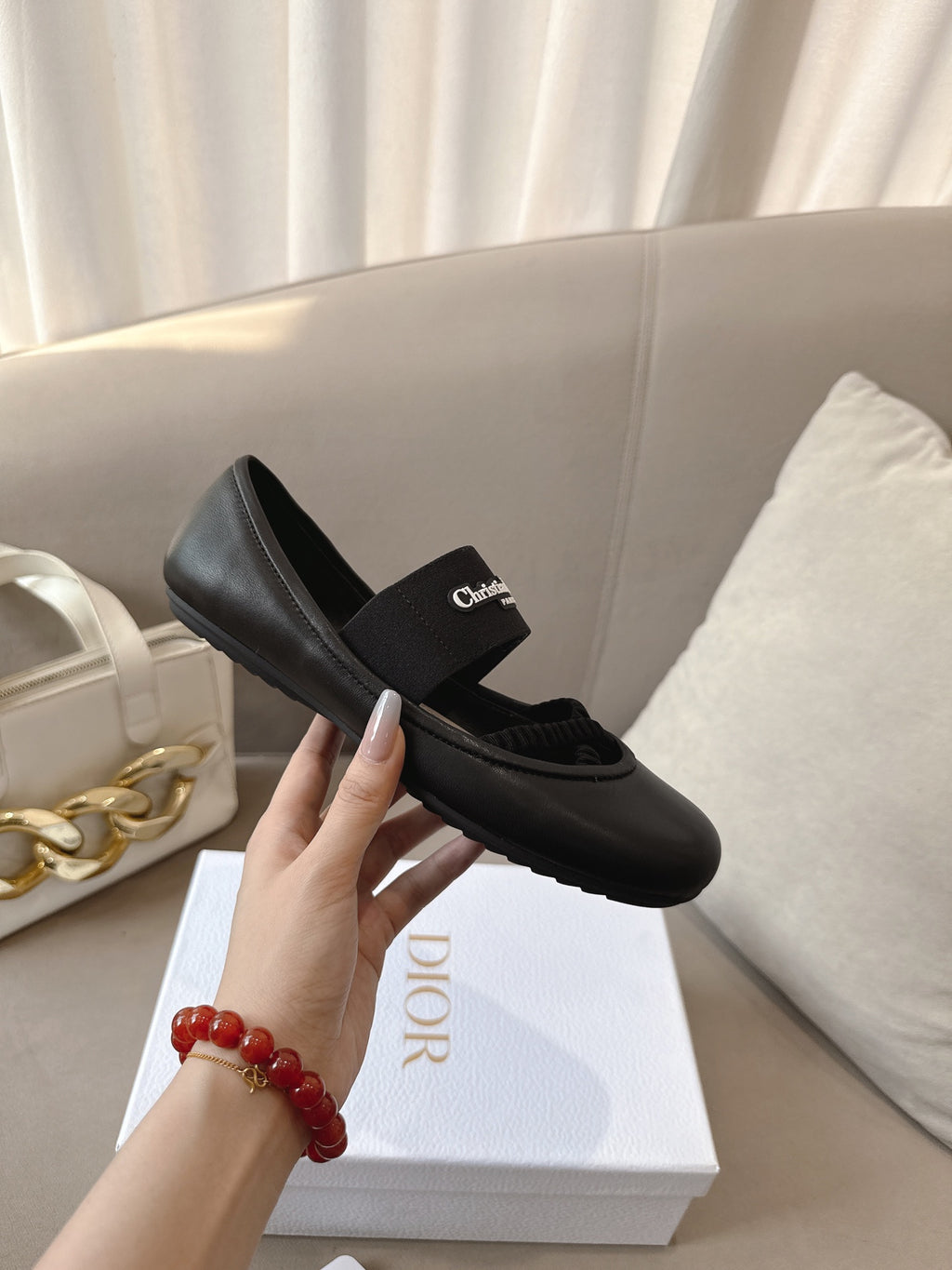 Black women's ballet flat with crisscross strap and logo patch, held in hand.