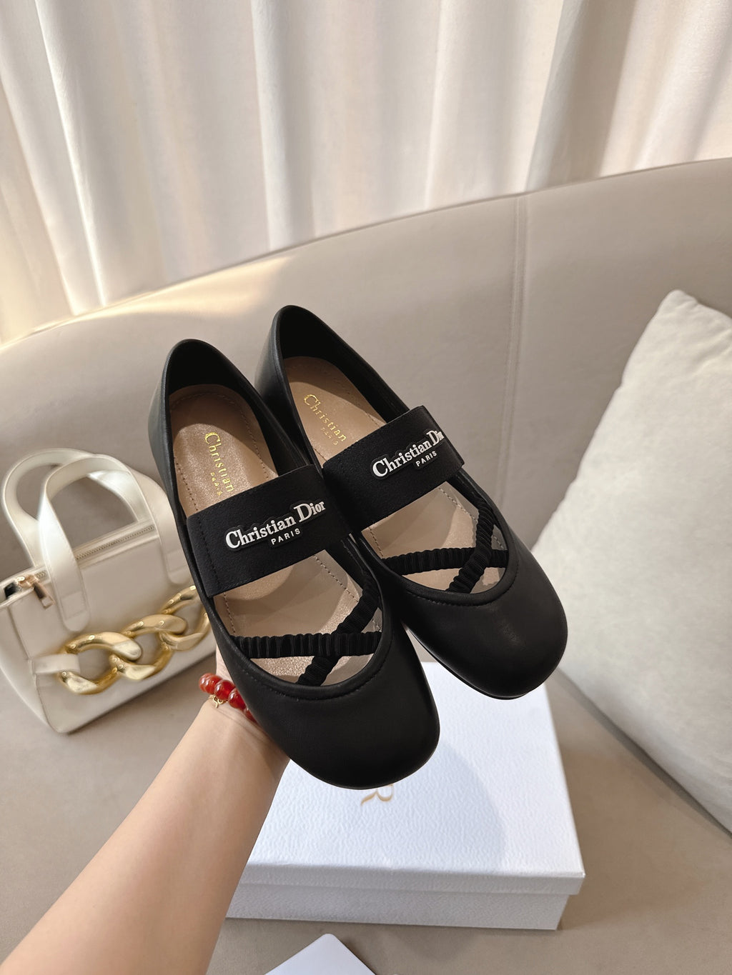 Black women's ballet flats with crisscross strap and logo patch, side view.