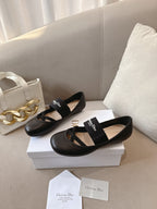 Black women's ballet flats with crisscross strap and logo patch, angled view.