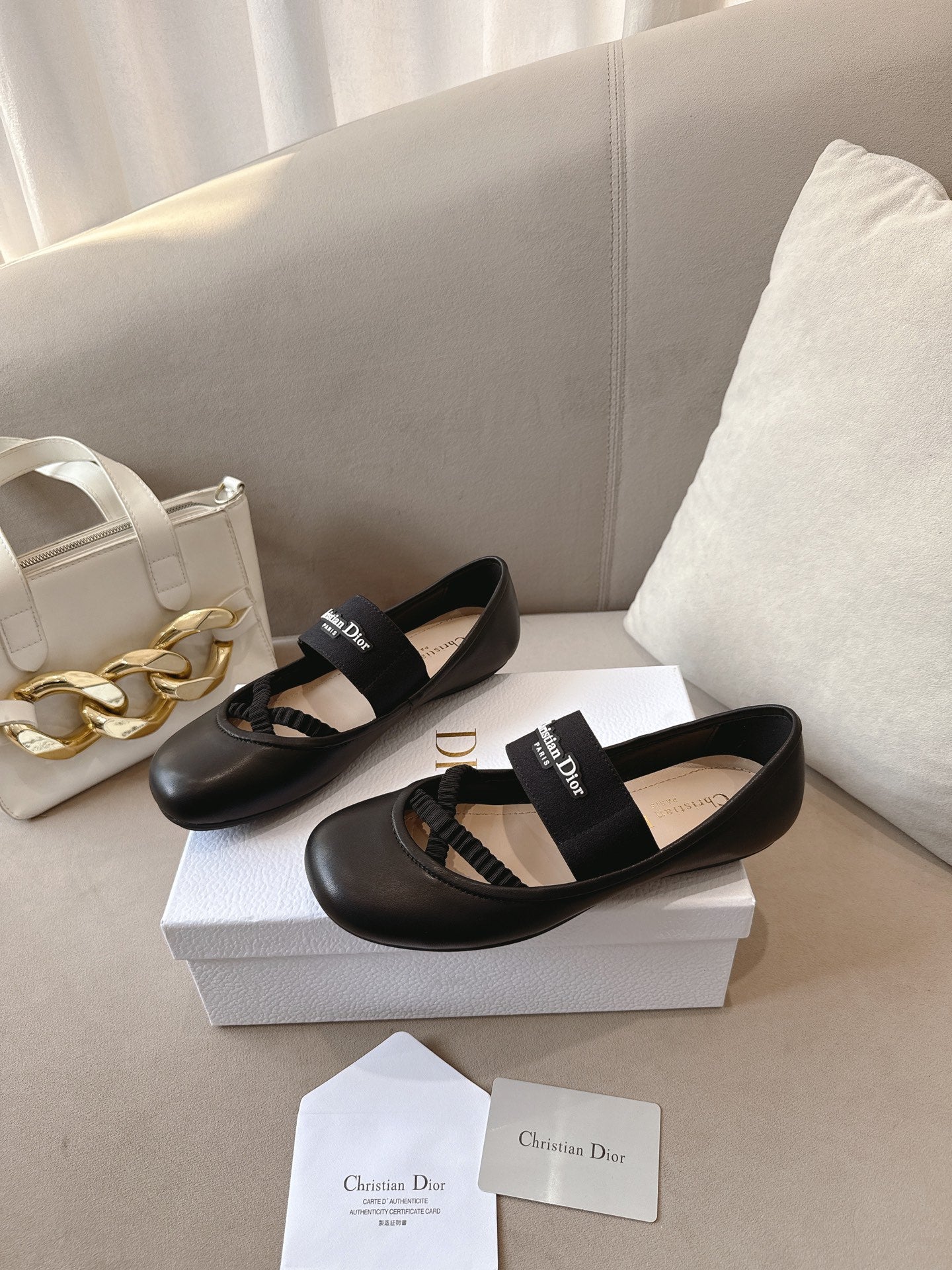 Black women's ballet flats with crisscross strap and logo patch, angled view.