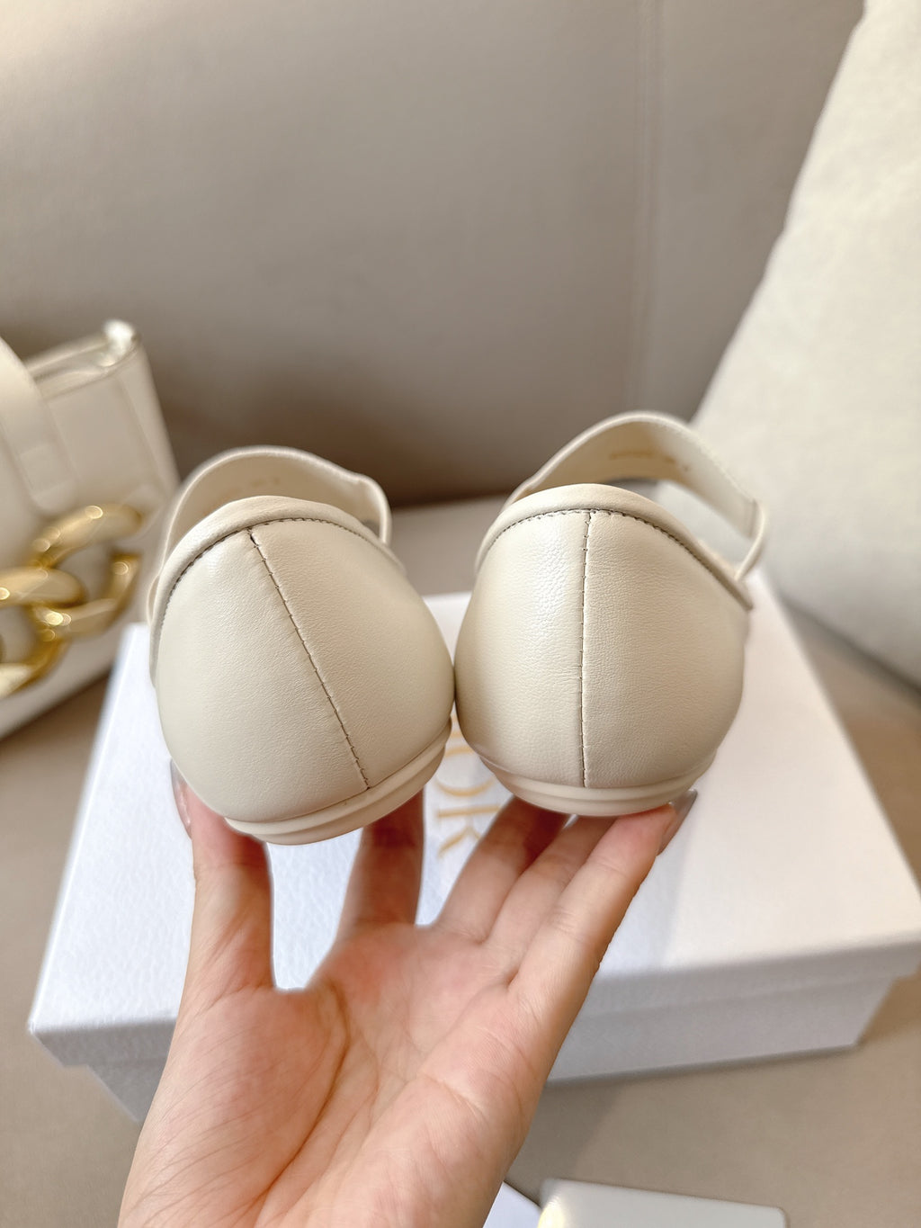 Heels of light cream Dior ballerina flats with rounded backs and logo heel label