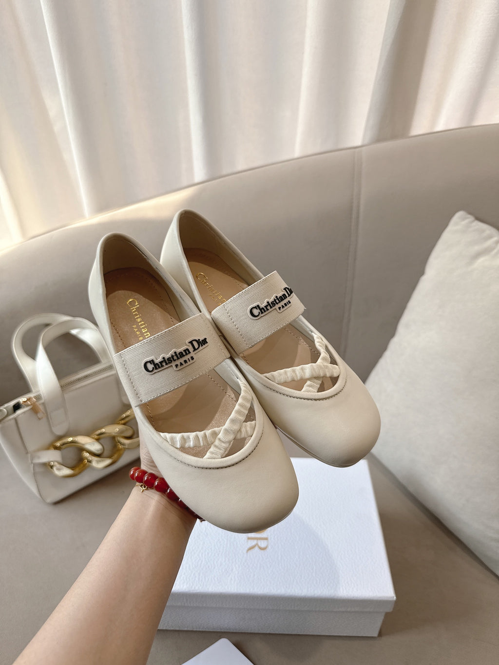 Pair of light cream Dior ballerina flats with logo labels and elastic straps