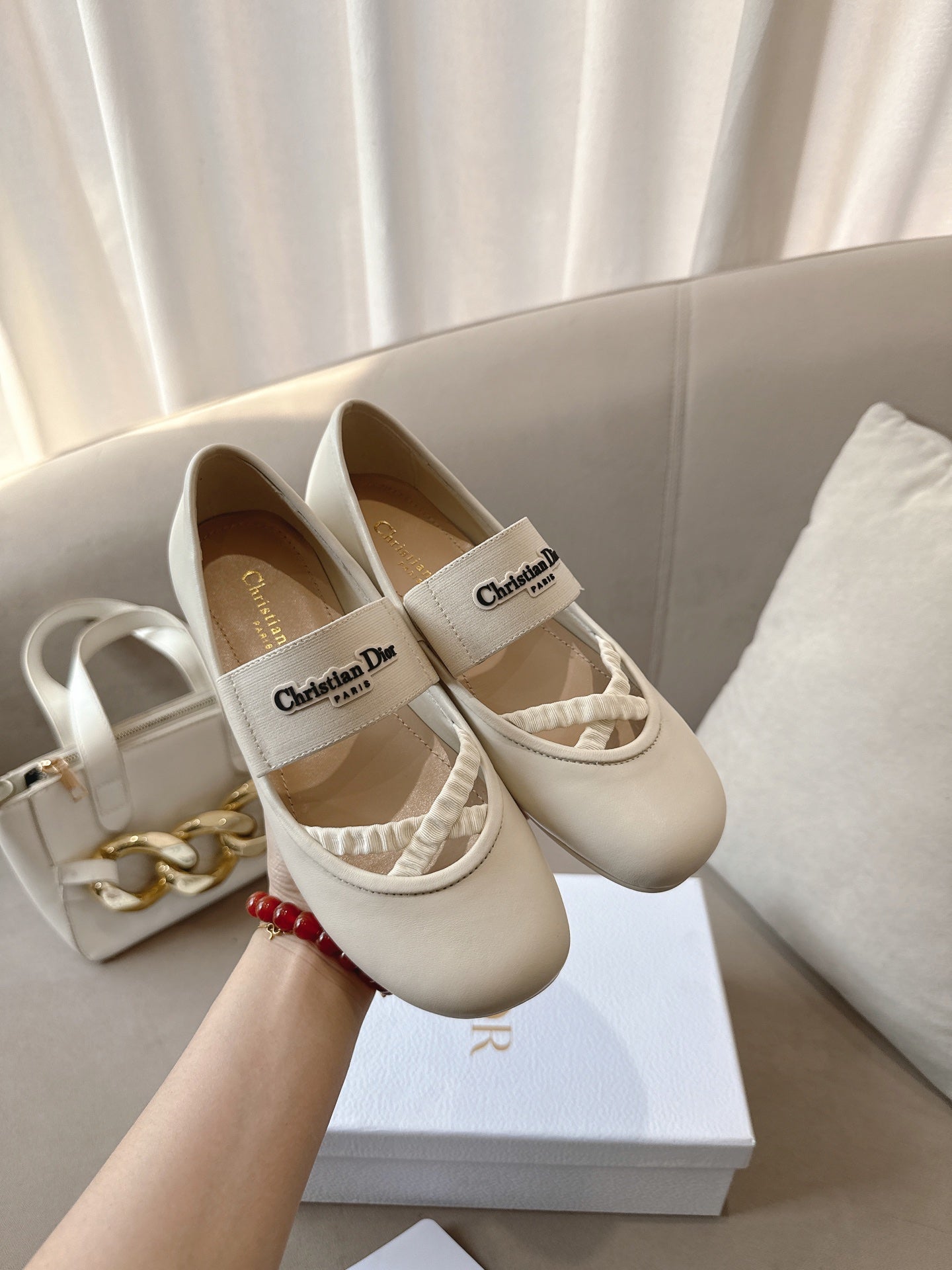 Pair of light cream Dior ballerina flats with logo labels and elastic straps