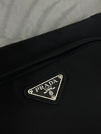 Prada bag front logo plaque on black fabric with stitched border