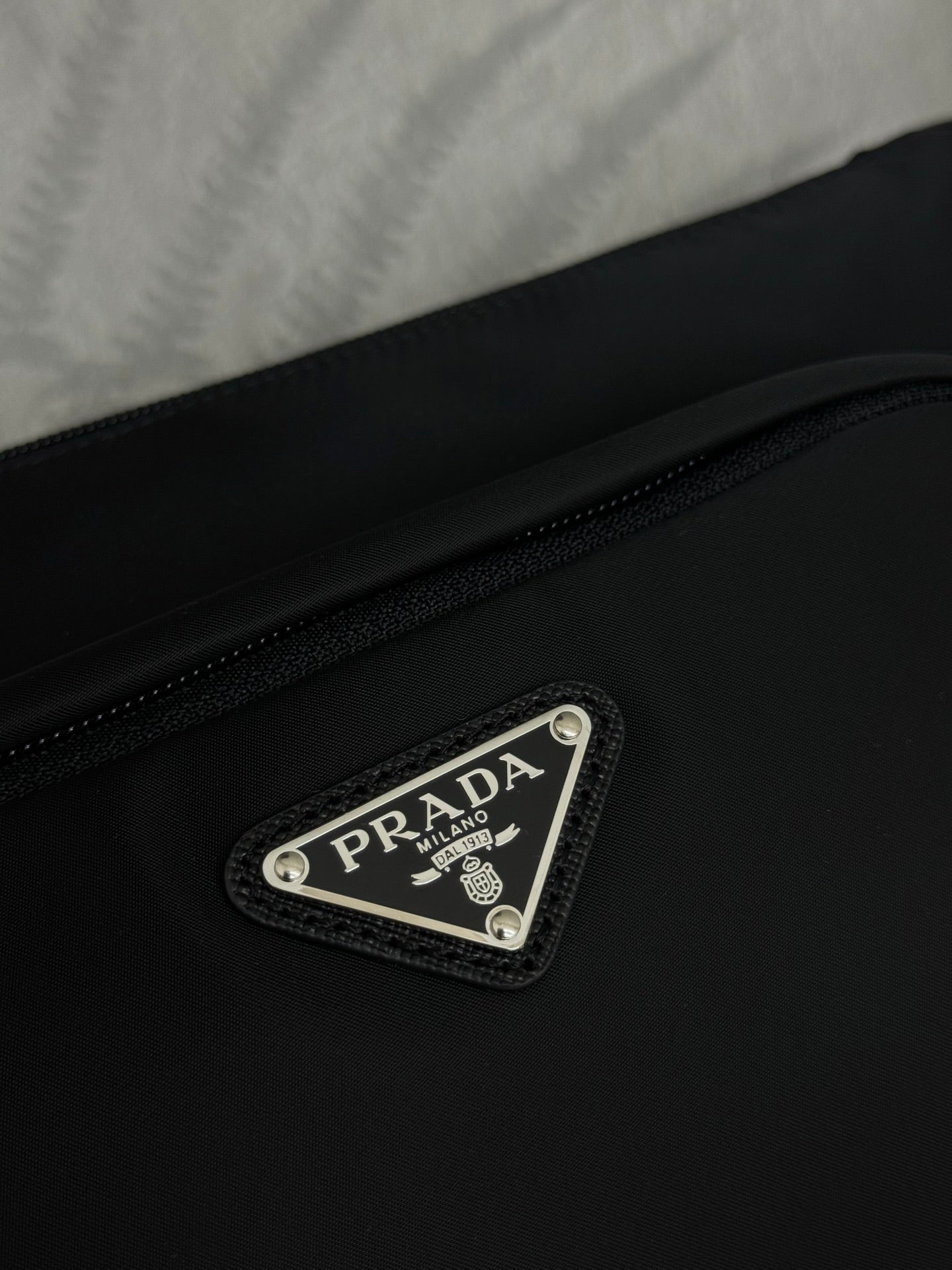 Prada bag front logo plaque on black fabric with stitched border