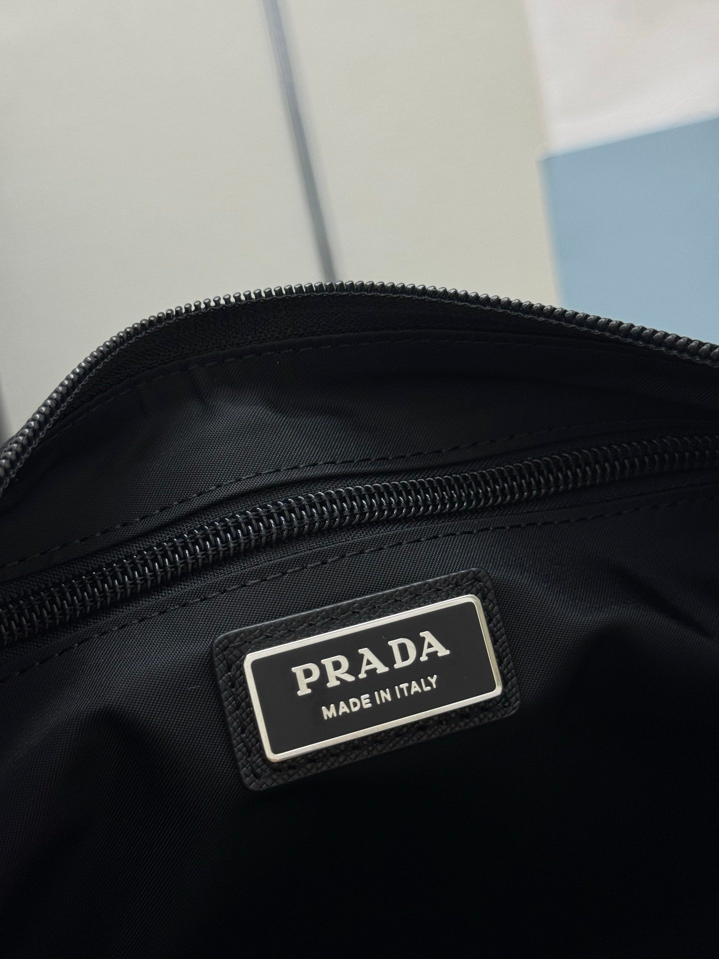 Prada bag brand label on black fabric, "Made in Italy" tag and zipper edge