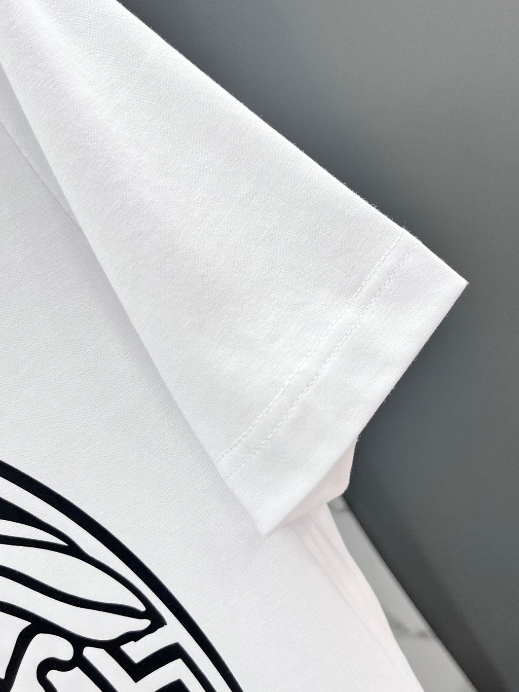 White Versace T-shirt sleeve close-up with black emblem print