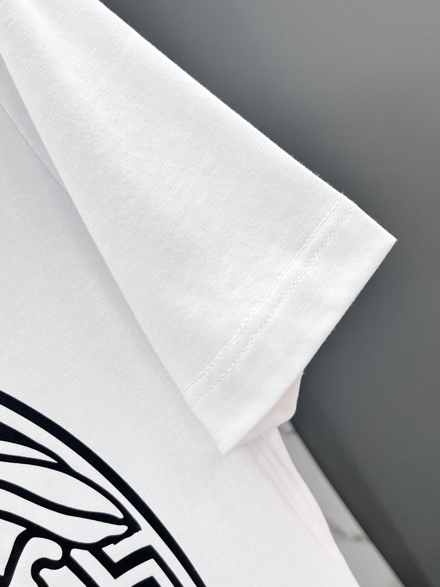 White Versace T-shirt sleeve close-up with black emblem print