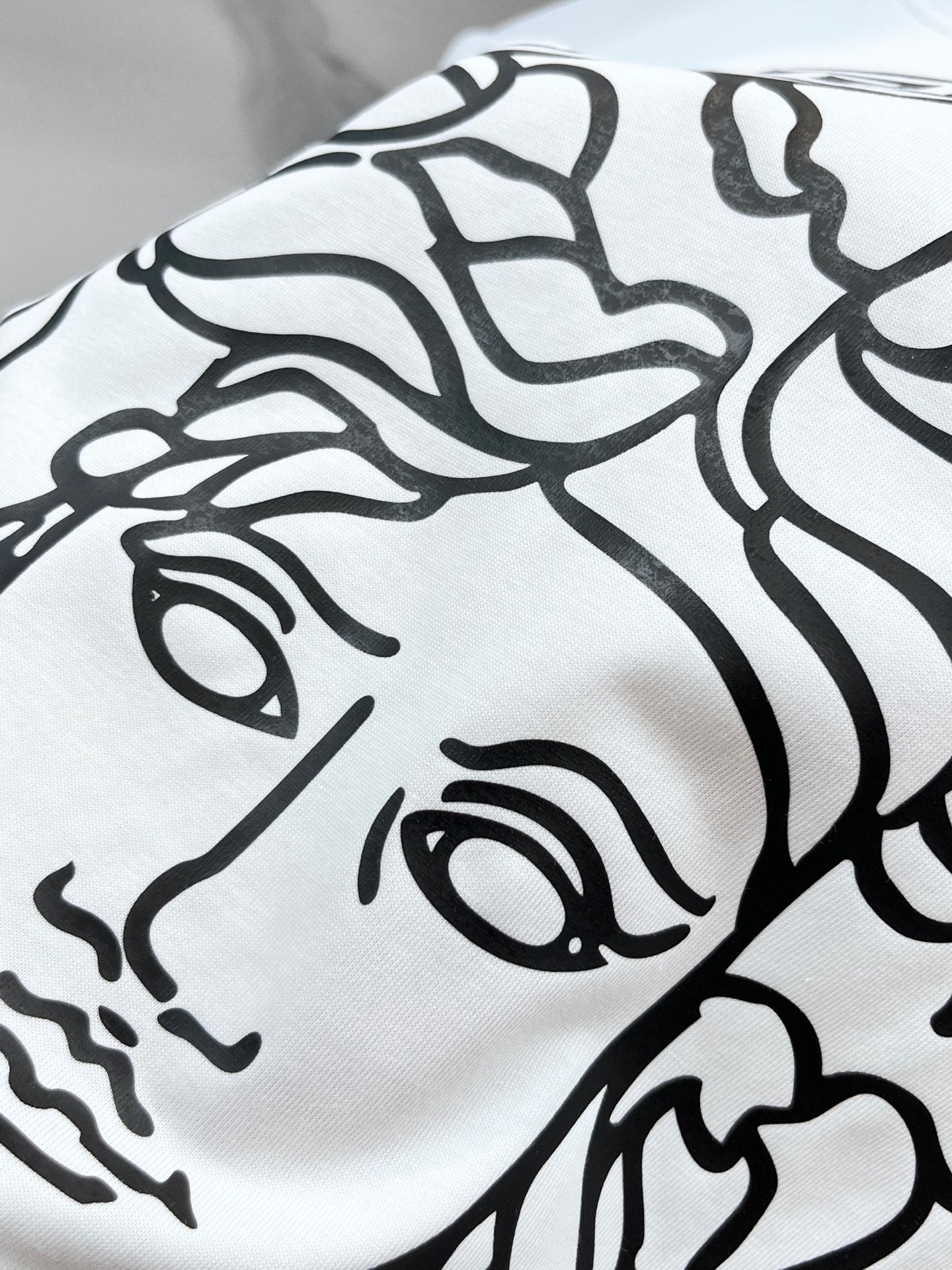 Versace white T-shirt close-up of bold black Medusa-style graphic on fabric