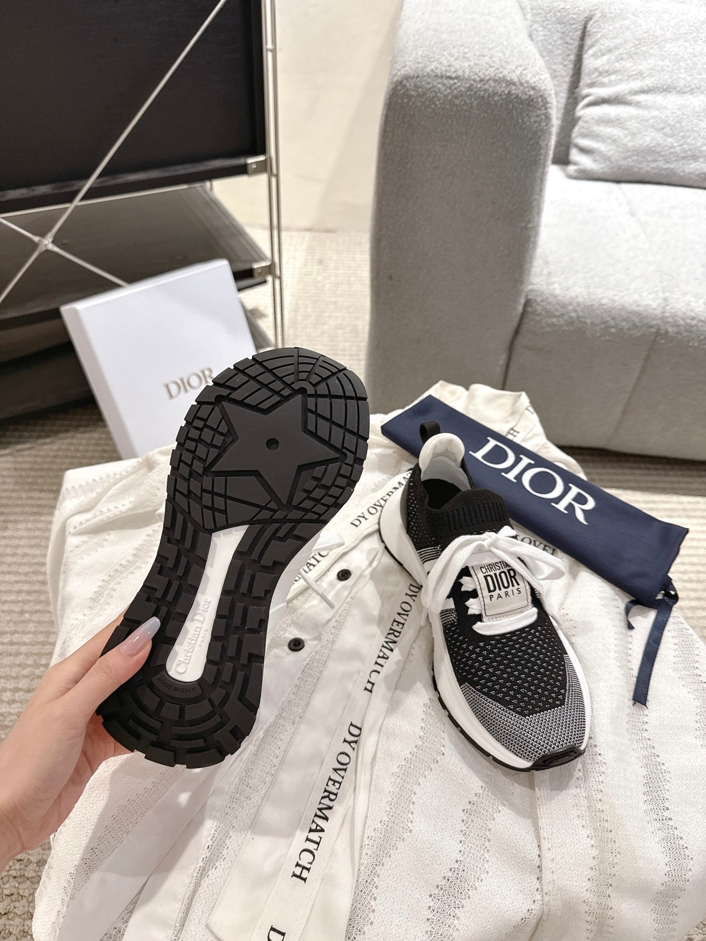 Unisex Dior sneaker outsole and side, black rubber tread with white accents