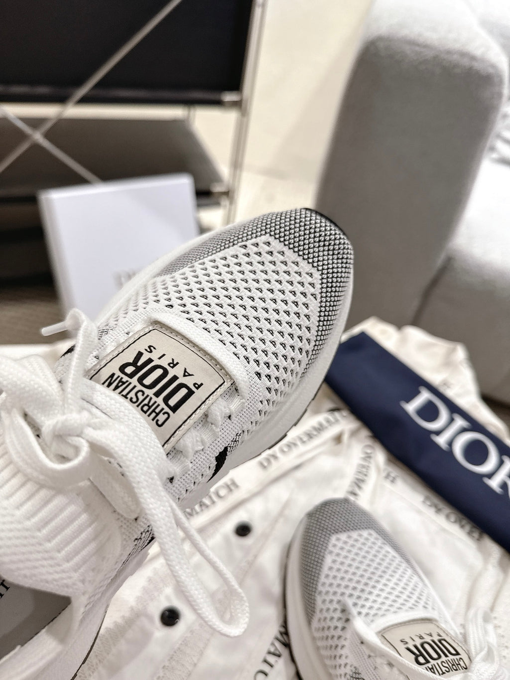White mesh sneaker close-up with black logo patch and white laces