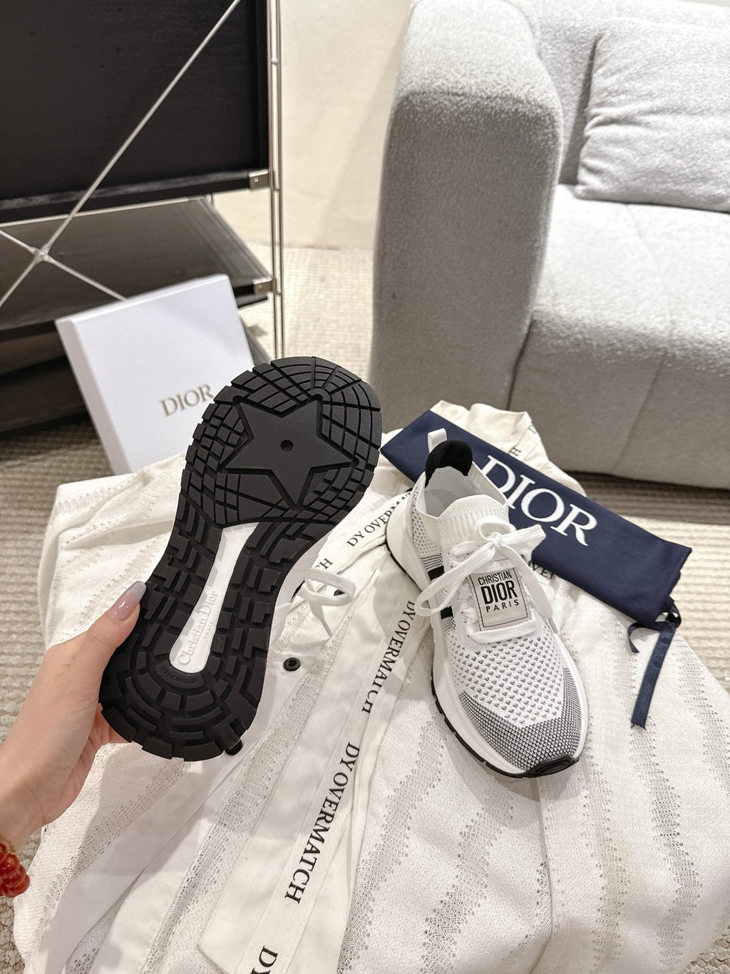 White lace-up sneakers with black outsole tread and Dior-branded heel tab