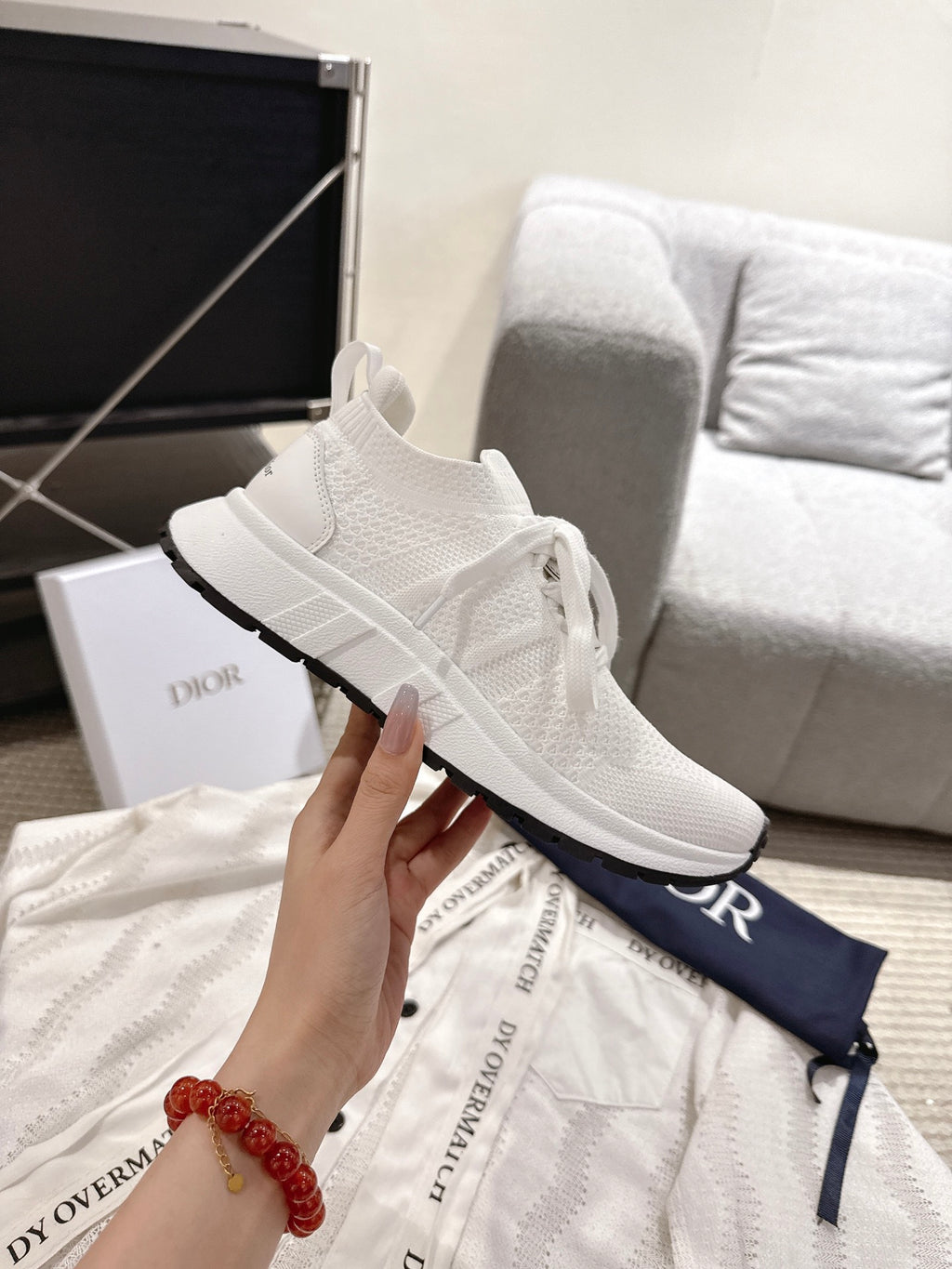 Dior unisex white sneaker with knit texture and black sole trim, shown in hand