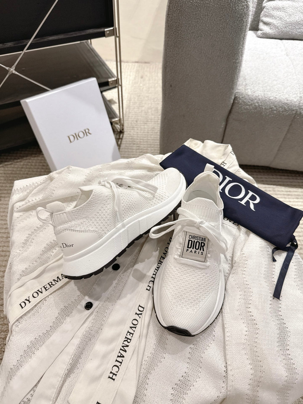 Dior unisex white sneakers with black-trim midsoles, laced and shown on cloth