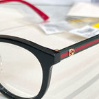 Gucci black eyeglass frame corner with green-and-red stripe and gold emblem.
