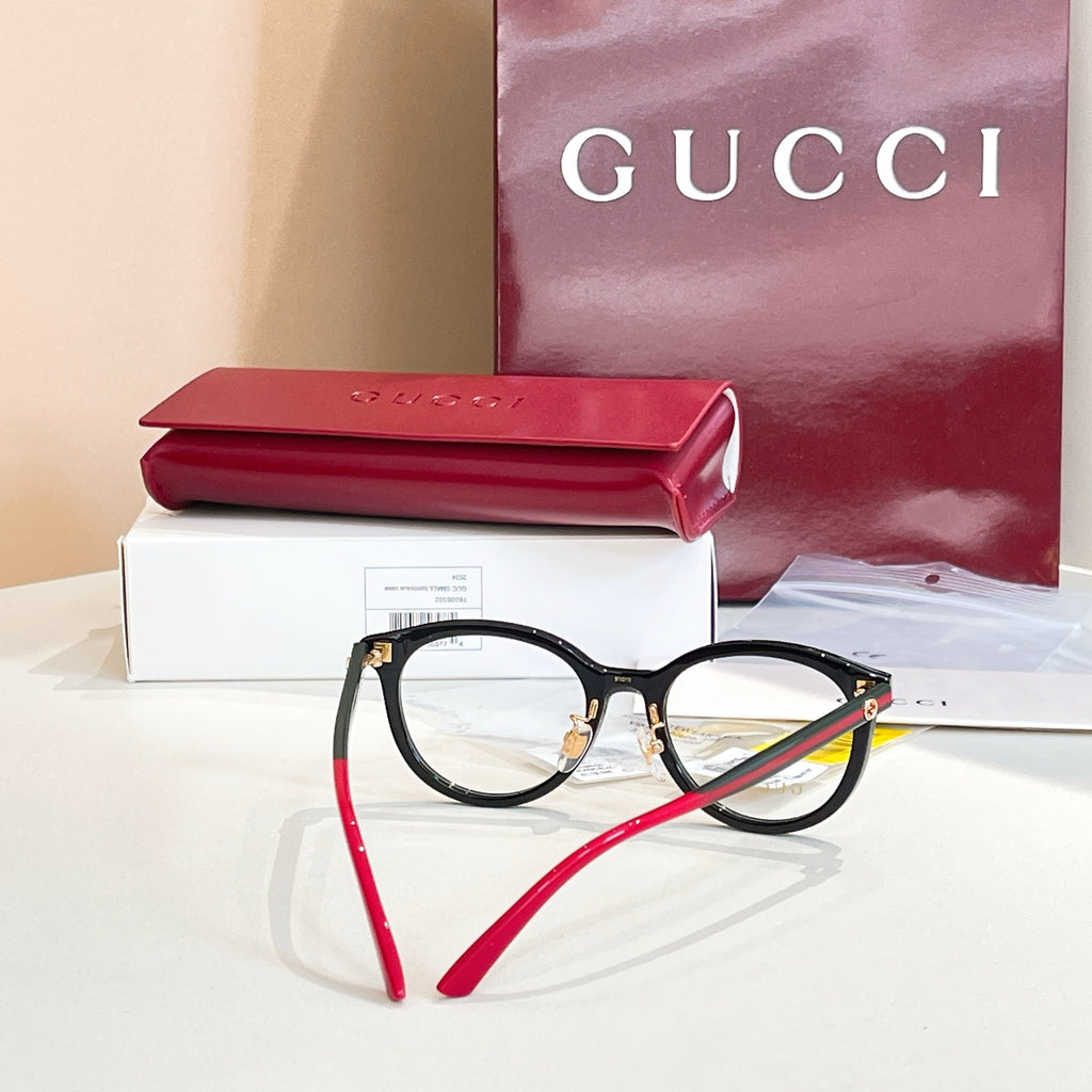 Gucci black round eyeglasses with red temple tips and gold hinge detail.