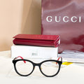 Gucci black round eyeglasses with red temple arms and gold logo detailing.