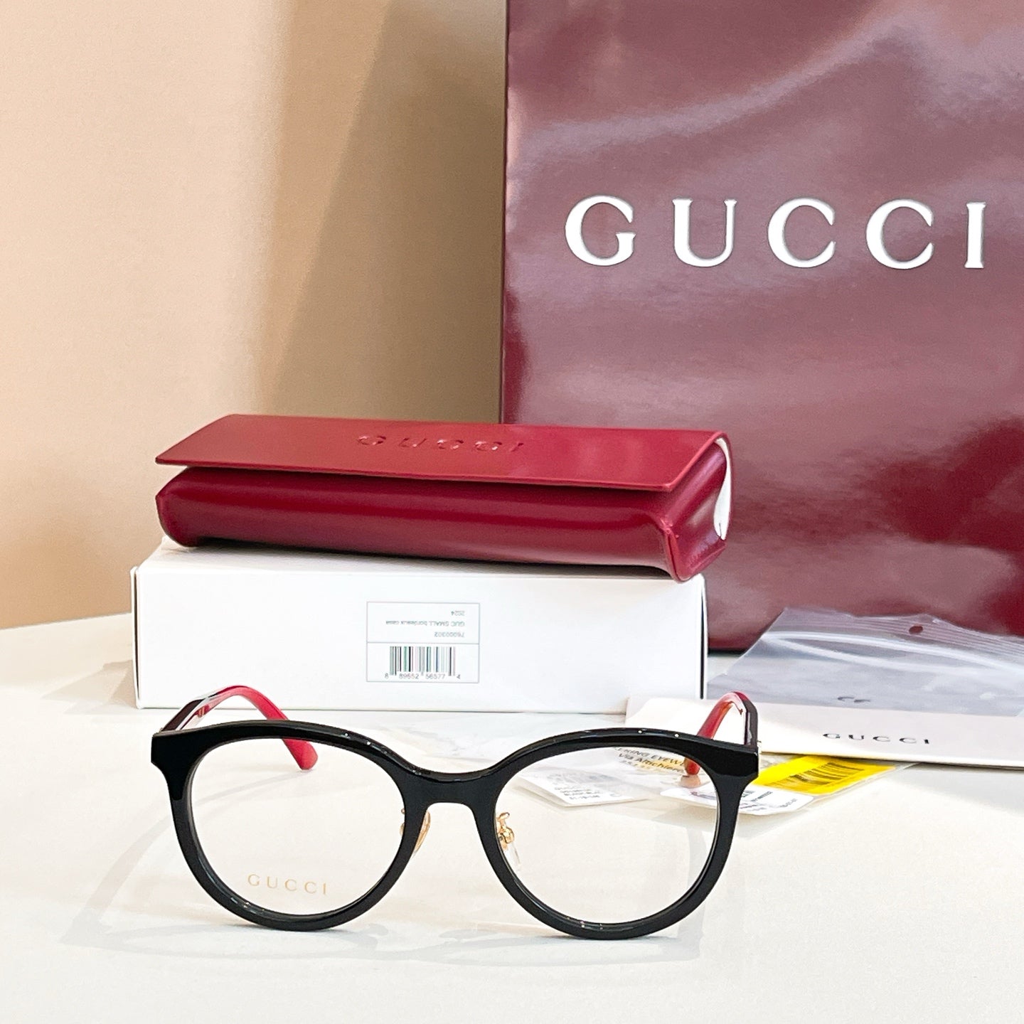 Gucci black round eyeglasses with red temple arms and gold logo detailing.
