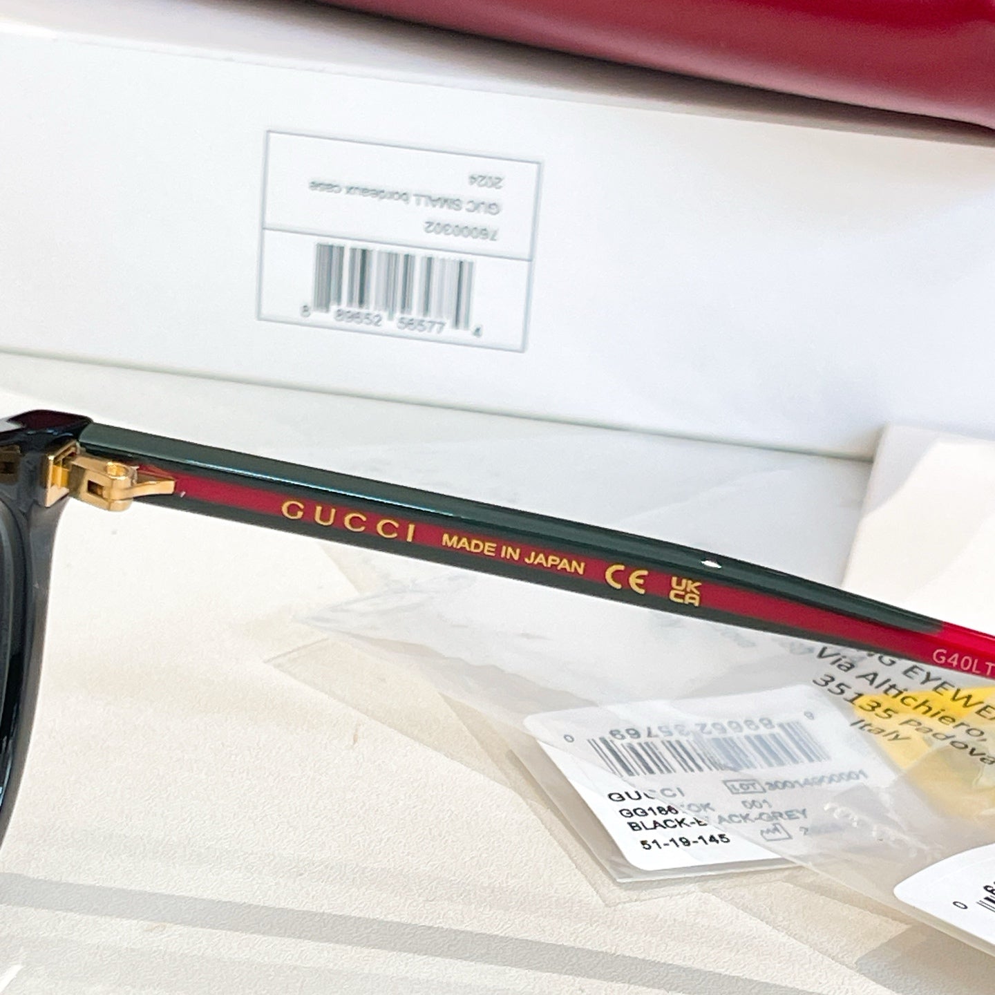 Gucci eyeglass temple arm detail with green-and-red stripe and gold hinge.