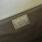 Gucci brand fabric label patch on dark interior lining with stitched border.